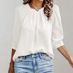 Blouse blanche élégante à manches longues, col rond, portée avec un jean bleu. Mode féminine chic, tenue décontractée tendance.