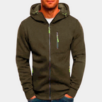 Homme portant un sweat à capuche zippé kaki avec poches et détails verts, mode décontractée, vêtement tendance pour homme, style urbain.