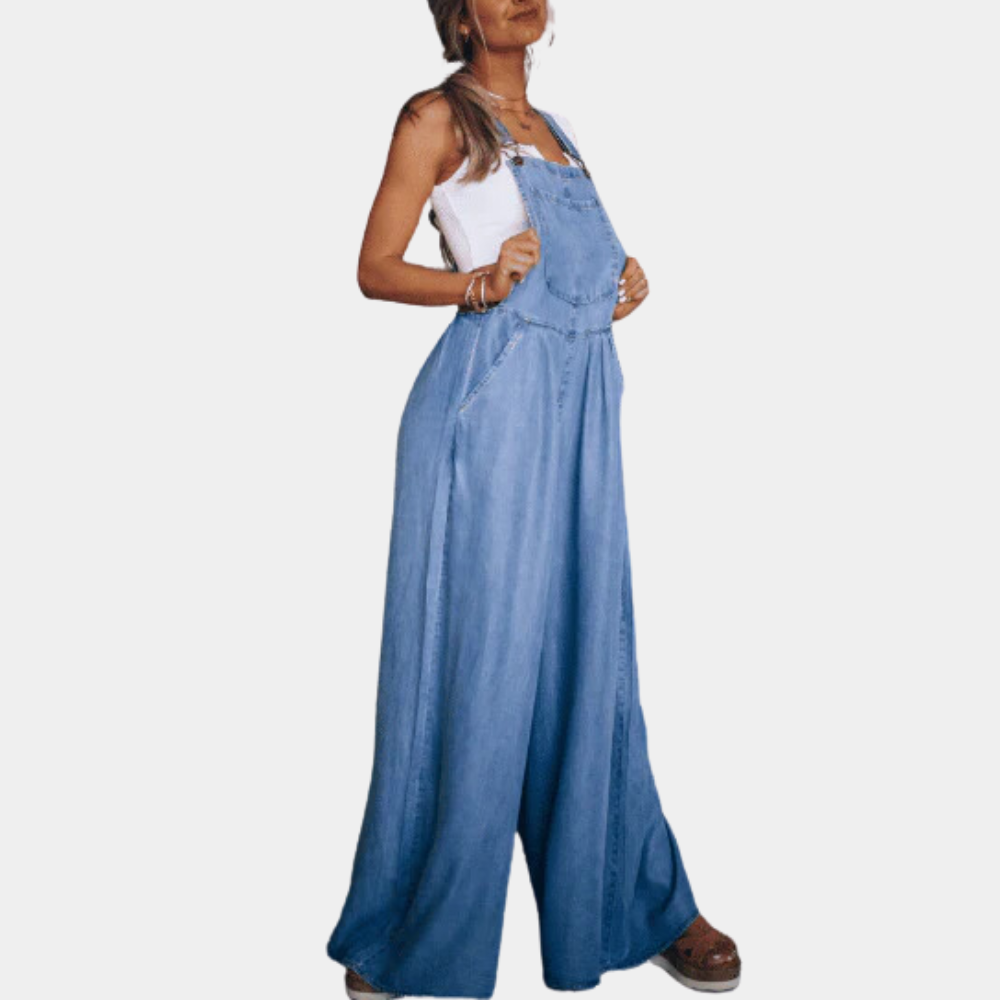 Femme portant une salopette en jean bleu ample, associée à un débardeur blanc. Mode décontractée, tendance, style estival.
