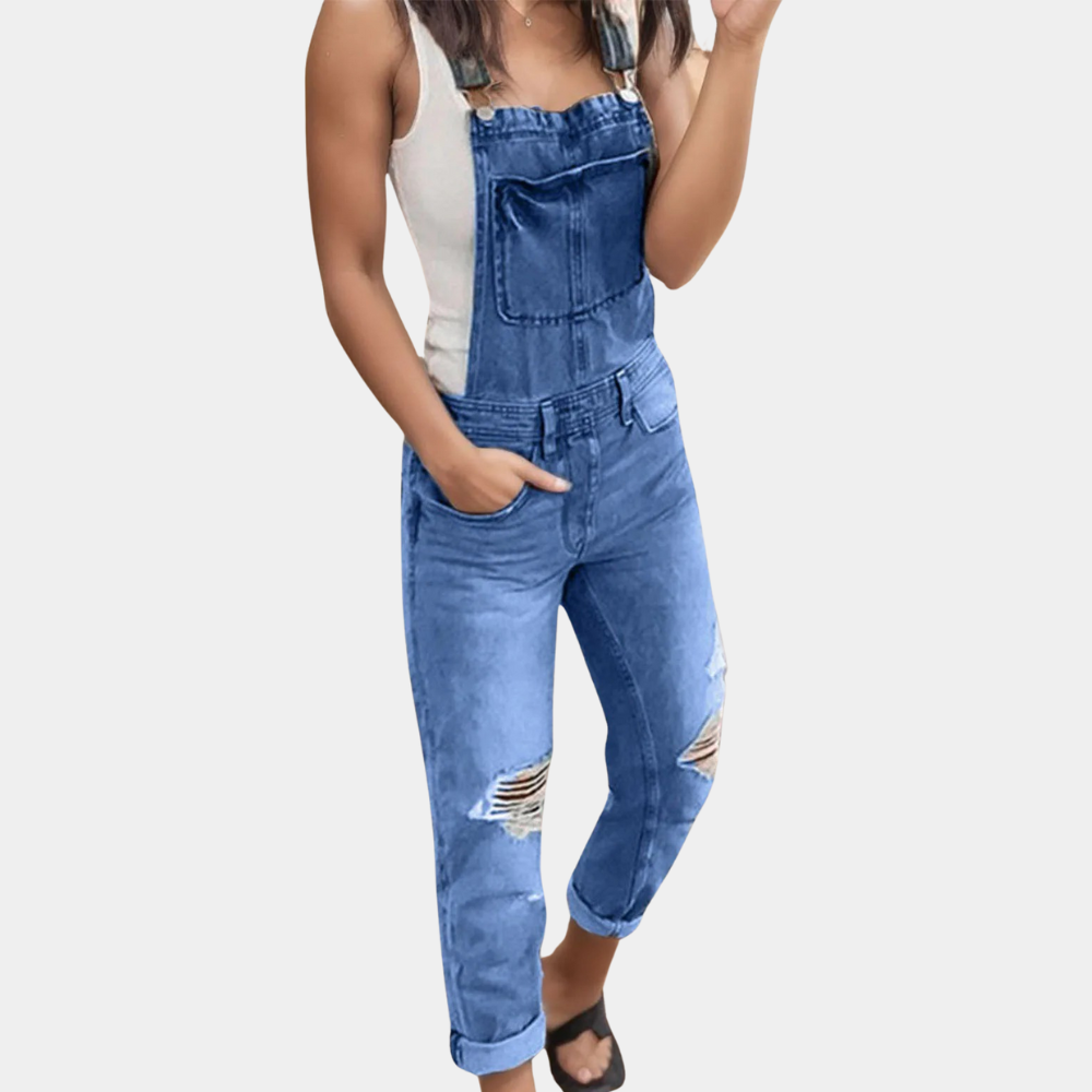 Salopette en jean bleu déchiré pour femme, portée avec un débardeur blanc. Mode décontractée, tendance, idéale pour un look estival chic.