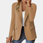 Femme portant un blazer beige élégant, chemise blanche et jeans, accessoirisée de bijoux dorés. Mode féminine chic, tenue décontractée tendance.