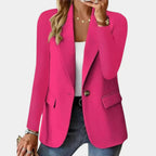 Femme portant un blazer rose vif, chemise blanche, jean bleu, accessoires dorés, style élégant et moderne, mode féminine tendance.