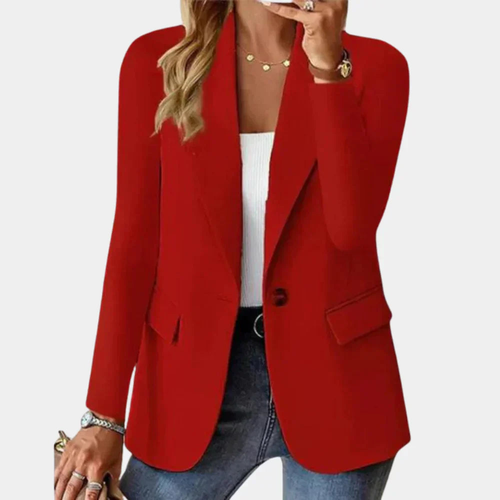 Femme portant un blazer rouge élégant, chemise blanche, jean bleu, accessoires dorés, sac à main beige. Mode féminine chic et tendance.