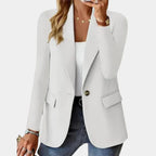 Femme portant un blazer blanc élégant, chemise blanche, jeans, et bijoux dorés. Mode féminine chic, tenue décontractée, style moderne.