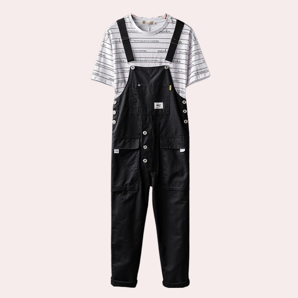 Salopette noire en denim avec boutons, portée sur un t-shirt rayé blanc et noir. Mode décontractée, tendance, vêtements pour homme.