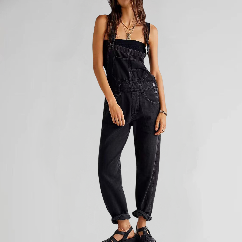 Femme portant une salopette noire en denim, style décontracté, avec des sandales noires. Mode tendance, tenue casual chic, look urbain moderne.