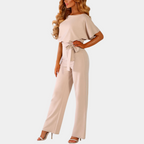 Femme portant une combinaison beige élégante avec ceinture, manches courtes et talons hauts. Mode féminine chic, tenue décontractée tendance.