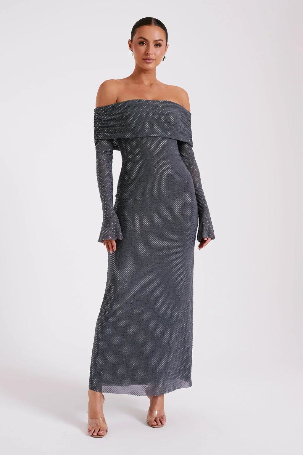 Robe longue grise à épaules dénudées, manches longues, portée par une femme. Élégante et moderne, idéale pour soirées et événements formels.