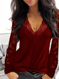 Femme portant un haut rouge en dentelle avec manches longues, col en V, collier doré, posant devant un fond blanc moderne. Mode féminine élégante.