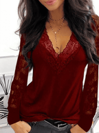 Femme portant un haut rouge en dentelle avec manches longues, col en V, collier doré, posant devant un fond blanc moderne. Mode féminine élégante.