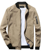 Veste bomber beige pour homme avec col noir, fermeture éclair, poche zippée sur la manche gauche, portée sur un t-shirt blanc. Mode masculine tendance.