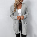 Femme portant un cardigan gris en tricot, débardeur blanc et jean noir. Mode automne, style décontracté, tenue élégante et confortable.