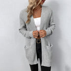 Femme portant un cardigan gris en tricot, débardeur blanc et jean noir. Mode automne, style décontracté, tenue élégante et confortable.