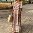 Robe longue bohème à motifs géométriques, femme tenant un sac en osier, marchant sur un chemin pavé, style estival décontracté.