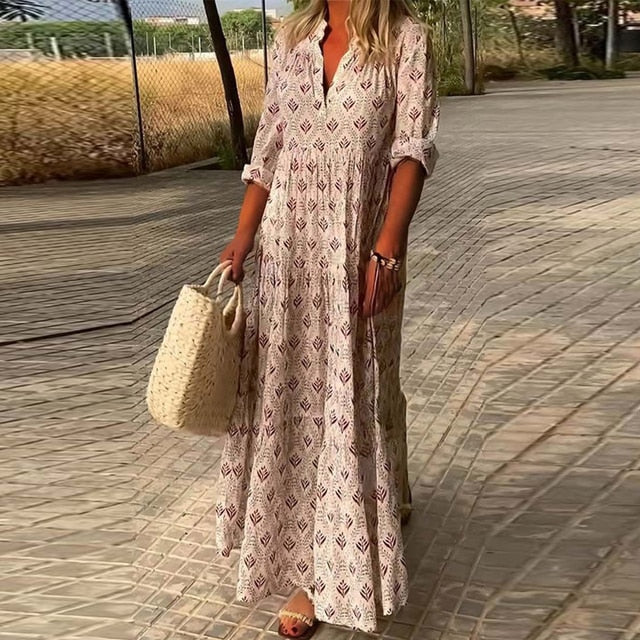 Robe longue bohème à motifs géométriques, femme tenant un sac en osier, marchant sur un chemin pavé, style estival décontracté.
