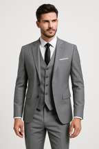 Homme en costume gris élégant avec cravate noire, chemise blanche et gilet assorti, posant sur fond blanc. Mode masculine, tenue formelle.