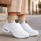 Chaussures de sport blanches modernes portées par une personne, sur un trottoir urbain. Sneakers tendance, confortables, idéales pour la marche en ville.