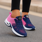 Chaussures de sport bleu et rose pour femme, semelle épaisse, design moderne, portées sur trottoir. Idéales pour course et fitness.