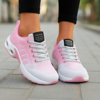 Baskets de sport roses et blanches pour femme sur trottoir, design moderne, lacets gris, semelle épaisse. Mode féminine, chaussures confortables.