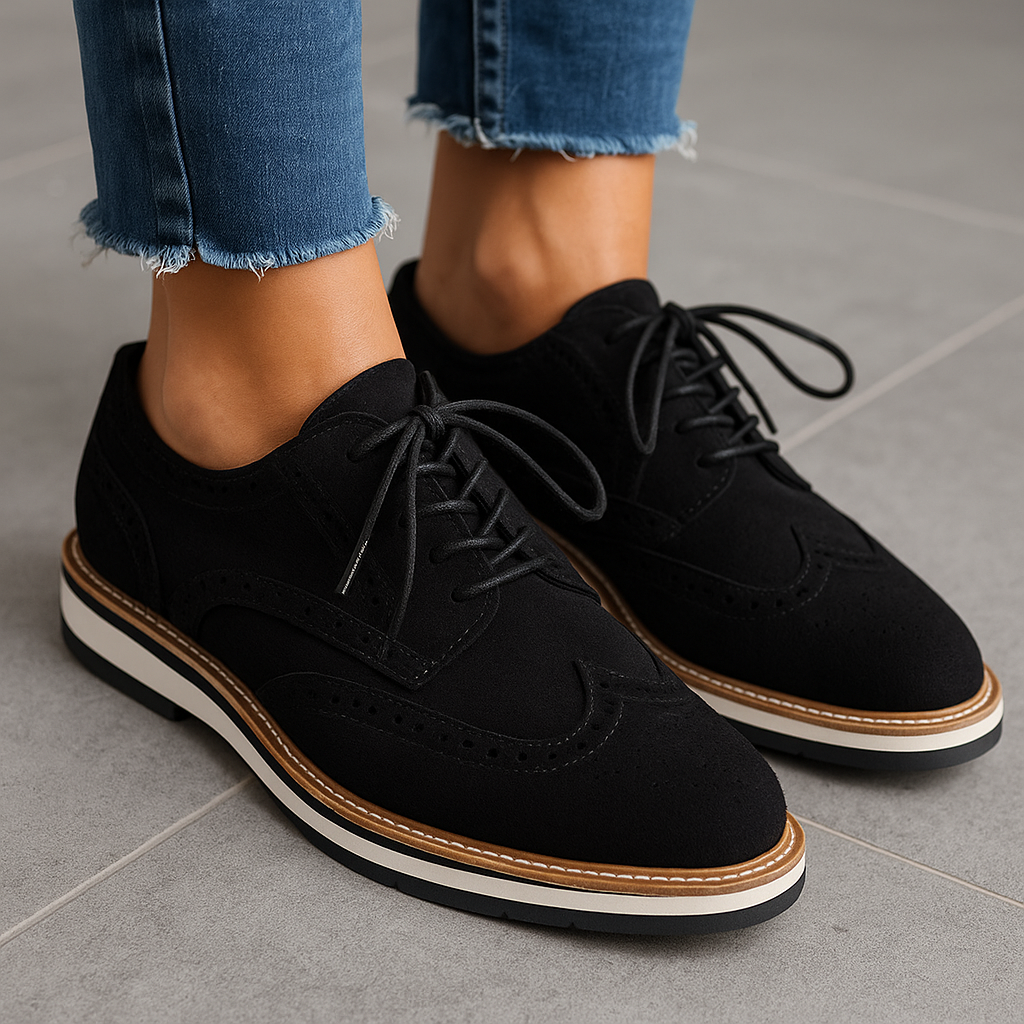 Chaussures derby noires en daim pour femme, lacets noirs, semelle blanche et marron, portées avec un jean bleu. Mode élégante et tendance.