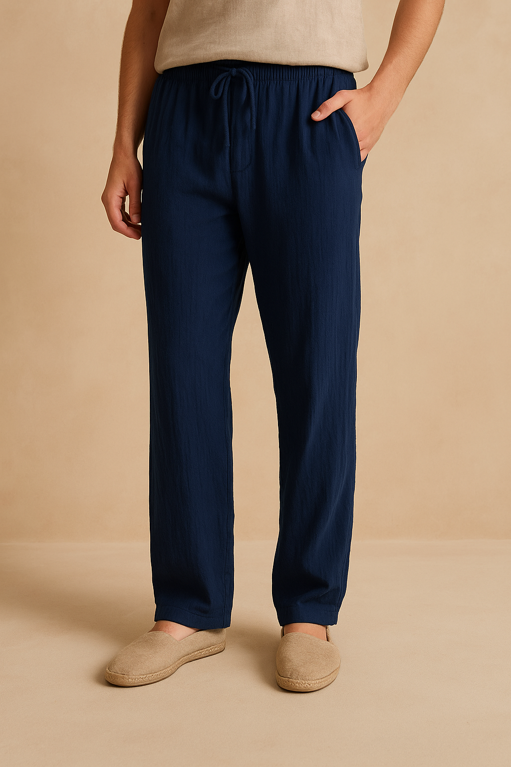 Pantalon bleu marine en lin pour homme, coupe décontractée, avec poches latérales et cordon de serrage, porté avec des espadrilles beiges.