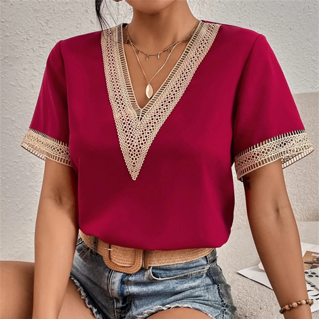 Femme portant un t-shirt rouge à col en V avec dentelle, assise, short en jean, ceinture beige. Mode féminine, style décontracté, tendance été.