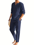 Homme en tenue décontractée bleue, chemise à manches longues et pantalon assorti, tenant un chapeau. Mode masculine élégante et moderne.
