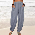 Pantalon ample en lin gris pour femme sur plage, poches avant, style décontracté, idéal pour l'été. Mode féminine, confort, vacances bord de mer.
