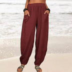 Pantalon ample en lin rouge bordeaux pour femme, poches avant, style décontracté, plage en arrière-plan, mode estivale confortable.