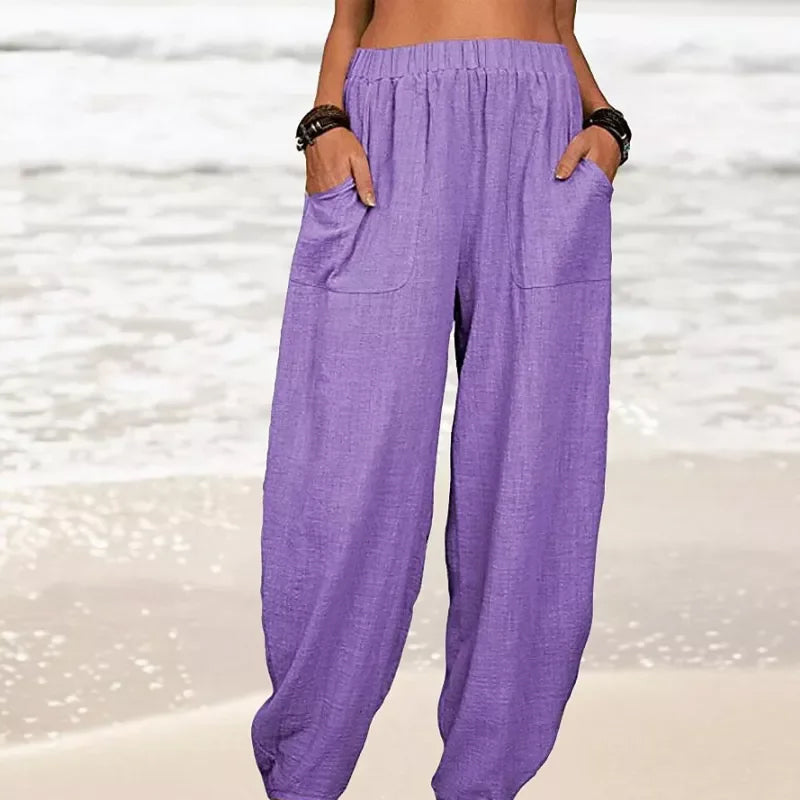 Pantalon ample violet en lin pour femme, poches avant, style décontracté, plage en arrière-plan. Mode estivale, confort, tendance.