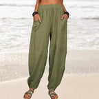 Pantalon ample en lin vert pour femme, poches avant, style décontracté, plage en arrière-plan, mode estivale, confort et élégance.