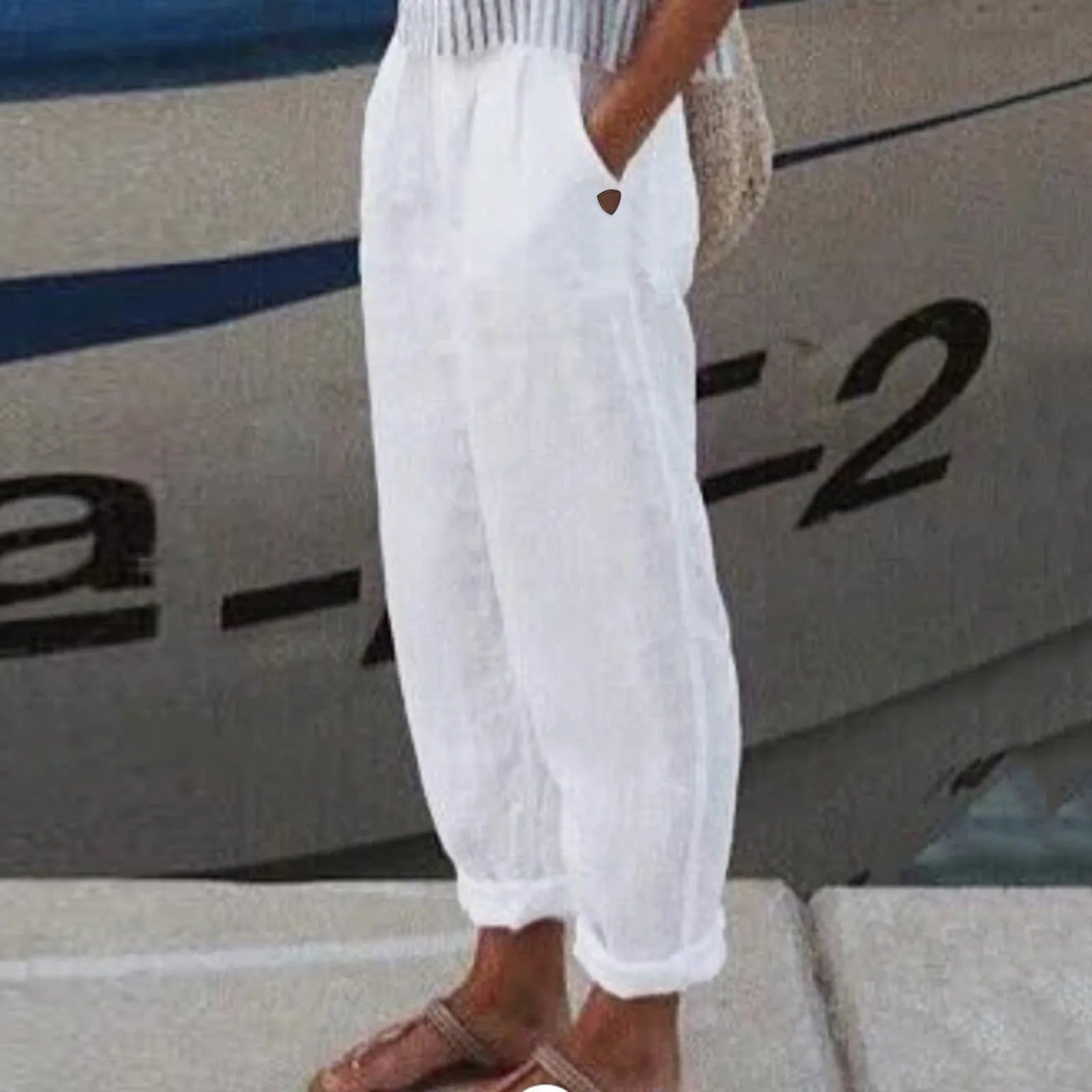 Pantalon blanc en lin pour femme, style décontracté, avec poches, idéal pour l'été, devant un bateau. Mode estivale, confort et élégance.