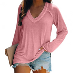 Femme portant un t-shirt rose à manches longues avec col en V, associé à un short en jean décontracté. Mode féminine, tenue estivale tendance.
