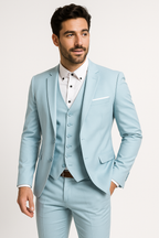 Homme en costume bleu clair élégant, chemise blanche, cravate absente, posant sur fond blanc. Mode masculine, tenue formelle, style moderne.