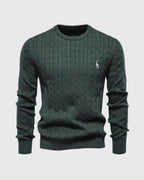Pull vert foncé en maille torsadée avec logo brodé, col rond, manches longues. Mode homme élégante, tendance automne-hiver, style décontracté.