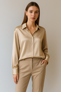 Femme portant une chemise en satin beige et un pantalon assorti, posant contre un fond neutre. Mode élégante, tenue professionnelle, style chic.
