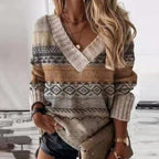 Femme portant un pull en laine à motifs géométriques, col en V, manches longues, avec un sac à main beige. Mode automne-hiver tendance.