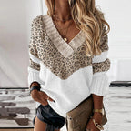 Femme portant un pull à motif léopard avec col en V, manches longues, et short noir, tenant un sac à main beige. Mode automne chic et tendance.