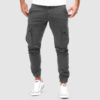 Pantalon cargo gris pour homme, style décontracté, poches latérales, coupe ajustée, idéal pour mode urbaine. Chaussures blanches visibles.