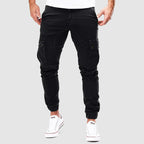 Pantalon cargo noir pour homme, style décontracté, poches latérales, coupe ajustée, idéal pour mode urbaine. Sneakers blanches visibles.