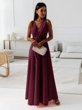 Femme élégante en robe longue bordeaux, tenant une pochette beige, dans un salon moderne. Mode féminine, style chic, tenue de soirée.
