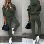 Femme en survêtement vert kaki, baskets blanches, portant un sac noir. Mode décontractée, tendance automne, style urbain chic.