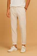 Pantalon homme à rayures verticales blanches et beiges, style décontracté, avec cordon de serrage, porté avec des baskets blanches.