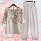 Tenue décontractée femme avec chemisier à motifs floraux et pantalon blanc ample. Mode printemps, style bohème chic, fond fleurs roses floues.