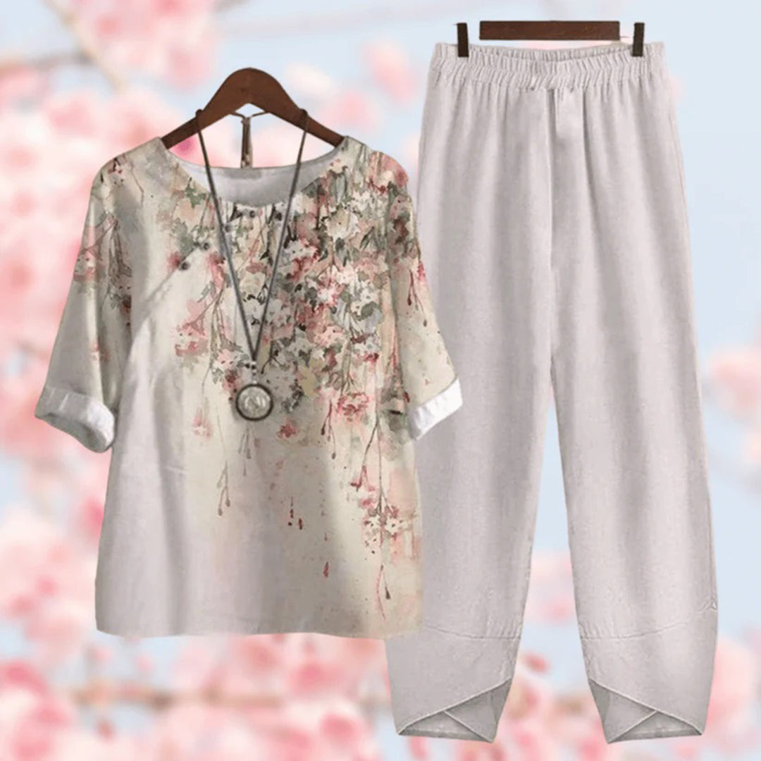 Tenue décontractée femme avec chemisier à motifs floraux et pantalon blanc ample. Mode printemps, style bohème chic, fond fleurs roses floues.