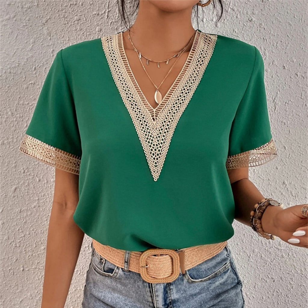 Femme portant un haut vert à col en V avec dentelle, ceinture beige, collier pendentif, et jean. Mode élégante, tenue décontractée chic.