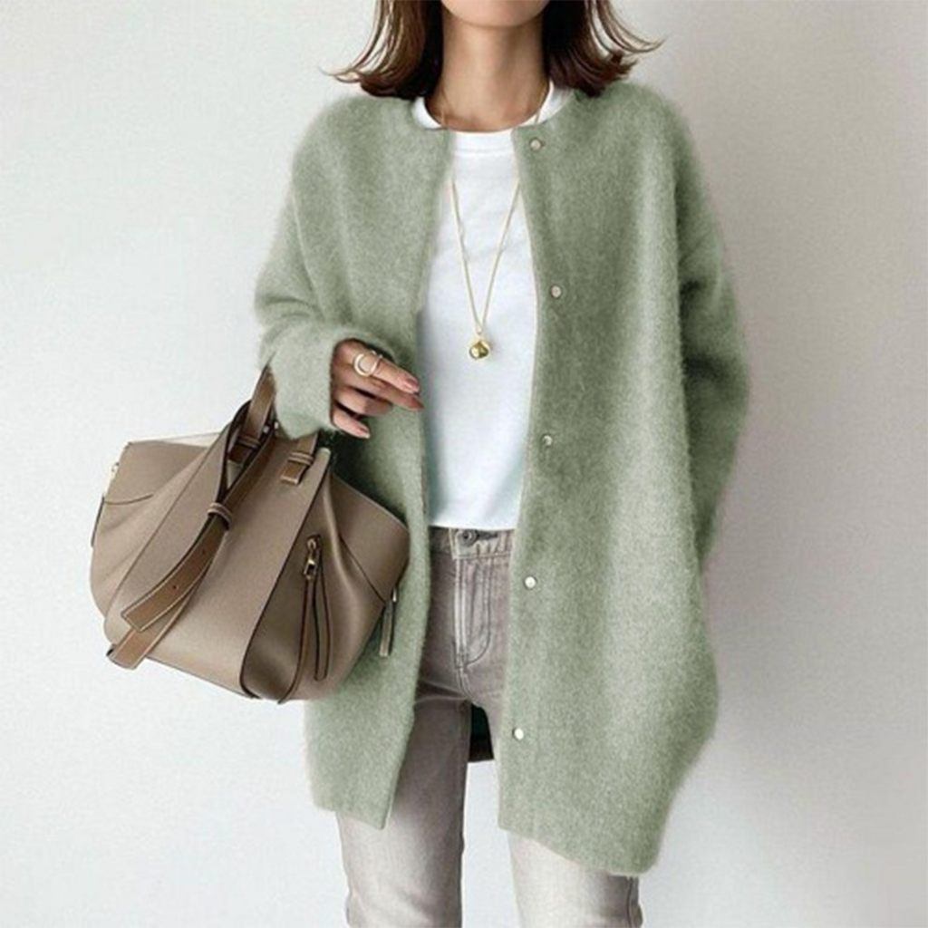 Femme portant un cardigan vert en laine, t-shirt blanc, jean beige, avec un sac à main taupe. Mode automne, style décontracté chic.