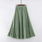 Jupe longue verte en lin, évasée, suspendue sur un cintre. Mode féminine, style bohème, tissu léger et fluide, idéale pour l'été.