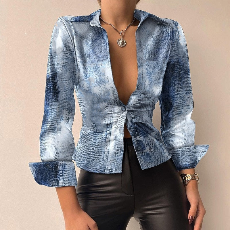 Chemisier en jean délavé bleu pour femme, manches longues, col ouvert, noué à la taille, porté avec un pantalon en cuir noir. Mode tendance.