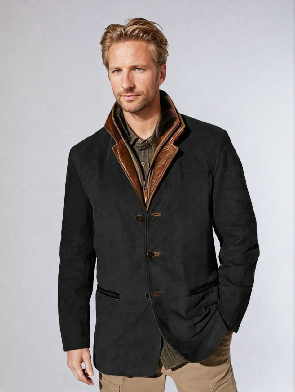 Homme portant une veste noire élégante avec col marron, chemise kaki et pantalon beige. Mode masculine, style automne-hiver, tenue chic.